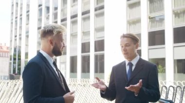 Modern ofis binasının önünde kendinden emin bir iş adamı ve meslektaşı. Finansal yatırımcılar dışarıda konuşuyorlar. Bankacılık ve iş.