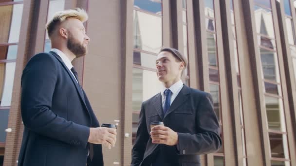 Уверенный бизнесмен и его коллега перед современным офисным зданием. Финансовые инвесторы говорят на открытом воздухе. Банковское дело. — стоковое видео