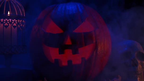 Calabaza riéndose de miedo y un viejo cráneo sobre un fondo oscuro. Halloween, brujería y magia. — Vídeo de stock