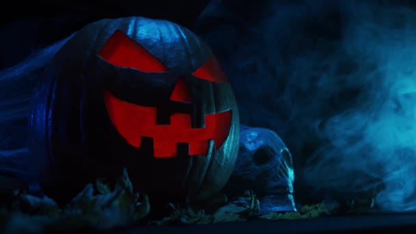 Skrattande pumpa och en gammal skalle med mörk bakgrund. Halloween, häxeri och magi. — Stockvideo