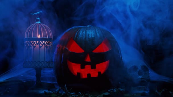 Gruselig lachender Kürbis und ein alter Totenkopf auf dunklem Hintergrund. Halloween, Hexerei und Magie. — Stockvideo