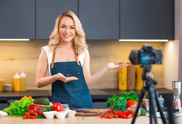 Jonge vrouw bereidt eten en organiseert een kookprogramma. De blogger stroomt vanuit de moderne keuken. Vegetarische gezonde voedselbereiding. — Stockfoto