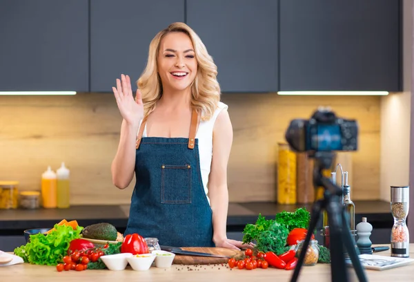 Young woman prepares food and hosts a cooking show. The blogger streams from modern kitchen. Vegetarian healthy food preparation. — Stock Photo, Image