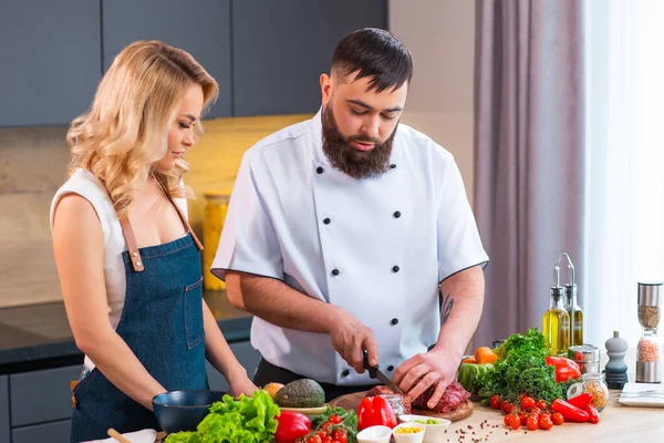 Jonge vrouw en man bereiden eten en organiseren een kookprogramma. De bloggers stromen vanuit de moderne keuken. Gezonde voedselbereiding. — Stockfoto