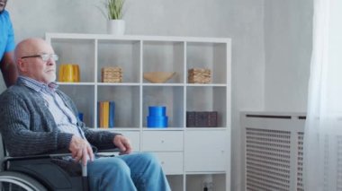 Afro-Amerikalı bakıcı ve tekerlekli sandalyedeki yaşlı engelli adam. Bakımevindeki profesyonel hemşire ve özürlü hasta. Yardım, rehabilitasyon ve sağlık hizmetleri.