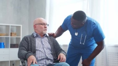 Afro-Amerikalı bakıcı ve tekerlekli sandalyedeki yaşlı engelli adam. Bakımevindeki profesyonel hemşire ve özürlü hasta. Yardım, rehabilitasyon ve sağlık hizmetleri.
