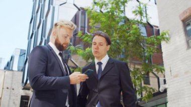 Modern ofis binasının önünde kendinden emin bir iş adamı ve meslektaşı. Finansal yatırımcılar dışarıda konuşuyorlar. Bankacılık ve iş konsepti.