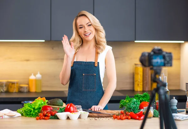 Young woman prepares food and hosts a cooking show. The blogger streams from modern kitchen. Vegetarian healthy food preparation. — Stock Photo, Image