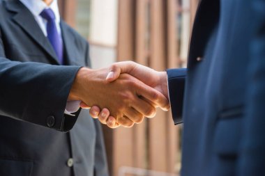 El sıkışın, yakın plan. İş adamı ve meslektaşı modern ofis binasının önünde el sıkışıyorlar. Finansal yatırımcılar açık havada. Bankacılık ve iş.