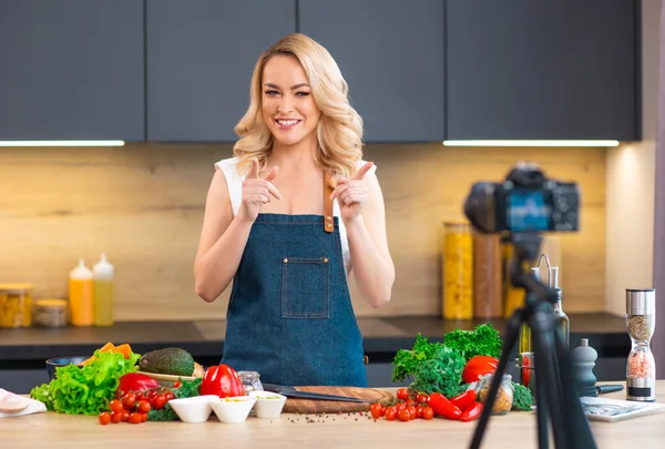 Young woman prepares food and hosts a cooking show. The blogger streams from modern kitchen. Vegetarian healthy food preparation. — Stock Photo, Image