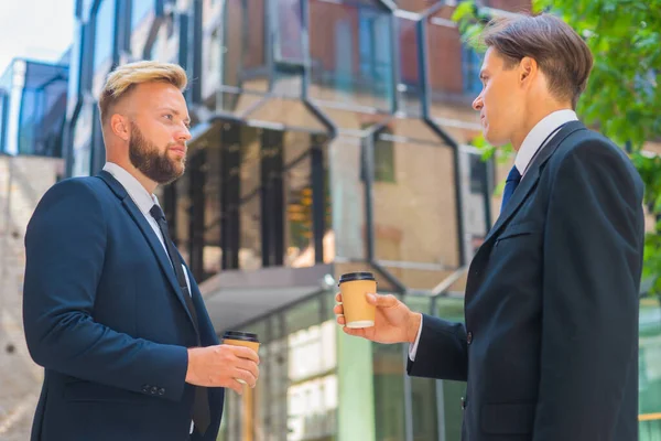 Fiducioso uomo d'affari e il suo collega di fronte a un moderno edificio per uffici. Gli investitori finanziari stanno parlando all'aperto. Settore bancario e commerciale. — Foto Stock