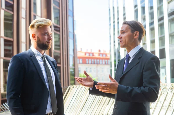 Självsäker affärsman och hans kollega framför en modern kontorsbyggnad. Finansiella investerare pratar utomhus. Banker och företag. — Stockfoto
