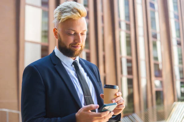 Selbstbewusster Geschäftsmann vor einem modernen Bürogebäude. Finanzinvestor setzt auf Smartphone-Outdoor Banken und Unternehmen. — Stockfoto