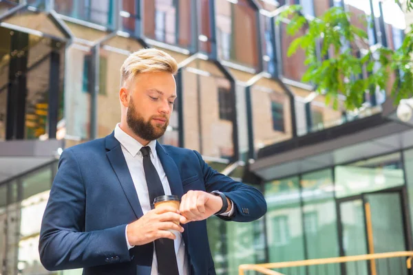 Selbstbewusster Geschäftsmann vor einem modernen Bürogebäude. Finanzinvestor geht ins Freie. Banken und Unternehmen. — Stockfoto