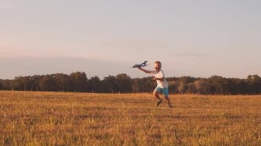 Çocuk gün batımında bir tarlada oyuncak bir uçakla oynuyor. Çocukluk, özgürlük ve ilham konsepti.
