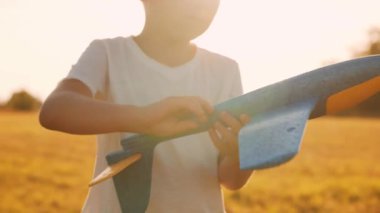 Çocuk gün batımında bir tarlada oyuncak bir uçakla oynuyor. Çocukluk, özgürlük ve ilham konsepti.