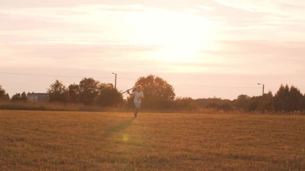 Boy plays with a toy plane in a field at sunset. The concept of childhood, freedom and inspiration. — Stock Video