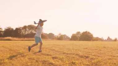 Çocuk gün batımında bir tarlada oyuncak bir uçakla oynuyor. Çocukluk, özgürlük ve ilham konsepti.