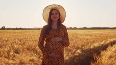 Günbatımında hamile bir kadın. Güzel bir genç kız bir çocuğun doğmasını umarak tarlada yürüyor. Annelik ve hamilelik kavramı.