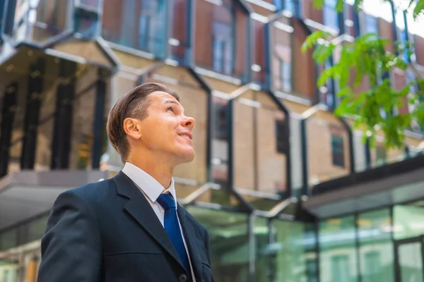 Homme d'affaires confiant devant un immeuble de bureaux moderne. Investisseur financier marche en plein air. Banques et entreprises. — Photo