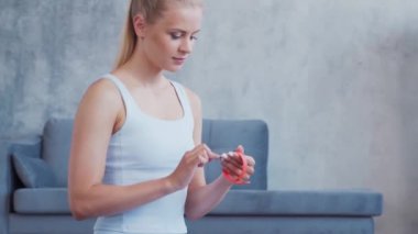 Spor giyim sektöründe genç ve sportif bir kız iç mekanda egzersiz yaparken akıllı saat kullanıyor. Formda ve narin sarışın kadın spor ve spor için geliyor. Sağlık sigortası, yağ yakma ve sağlık..