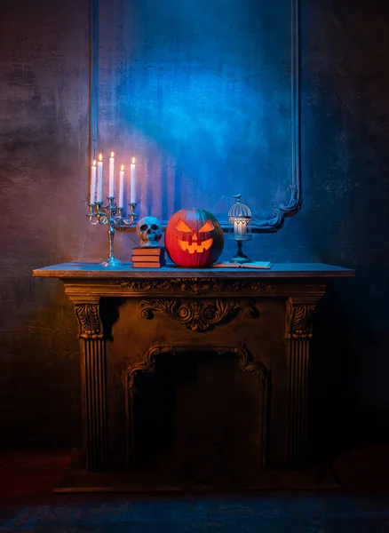 Läskigt skrattande pumpa och gammal skalle på antik gotisk öppen spis. Halloween, häxeri och magi. — Stockfoto