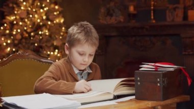 Noel ağacının yanında oturup kitap okuyan şirin bir çocuk. Çocuk evde yeni yıla hazırlanıyor. Mevsimlik kavram