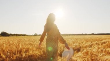 Günbatımında hamile bir kadın. Güzel bir genç kız bir çocuğun doğmasını umarak tarlada yürüyor. Annelik ve hamilelik kavramı.