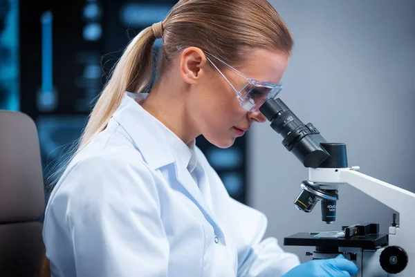 Kvinnlig läkare arbetar i ett modernt vetenskapligt laboratorium med hjälp av utrustning och datateknik. Forskaren forskar och utvecklar nya vacciner. Vetenskap och hälsovård. — Stockfoto