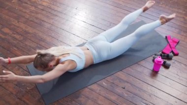 Spor giyimli genç ve sportif kız iç mekanda egzersiz yapıyor. Formda ve narin sarışın kadın spor ve spor için geliyor. Sağlık sigortası, yağ yakma ve sağlık..