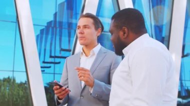 Modern ofis binasının önünde kendinden emin Afro-Amerikan iş adamı ve meslektaşı. Finansal yatırımcılar dışarıda konuşuyorlar. Bankacılık ve iş.
