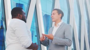 Modern ofis binasının önünde kendinden emin Afro-Amerikan iş adamı ve meslektaşı. Finansal yatırımcılar dışarıda konuşuyorlar. Bankacılık ve iş.