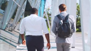 Modern ofis binasının önünde kendinden emin Afro-Amerikan iş adamı ve meslektaşı. Finansal yatırımcılar dışarıda konuşuyorlar. Bankacılık ve iş.