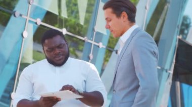 Modern ofis binasının önünde kendinden emin Afro-Amerikan iş adamı ve meslektaşı. Finansal yatırımcılar dışarıda konuşuyorlar. Bankacılık ve iş.