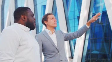 Modern ofis binasının önünde kendinden emin Afro-Amerikan iş adamı ve meslektaşı. Finansal yatırımcılar dışarıda konuşuyorlar. Bankacılık ve iş.