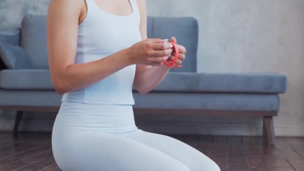 Jong en sportief meisje in sportkleding is met behulp van slimme horloge, terwijl het doen van oefeningen in huis interieur. Fit en slanke blonde vrouw gaat in voor sport en fitness. Gezondheidszorg, vetverbranding en welzijn. — Stockvideo