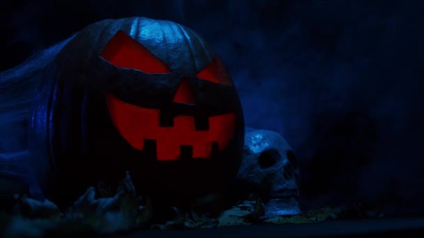 Skrattande pumpa och en gammal skalle med mörk bakgrund. Halloween, häxeri och magi. — Stockvideo