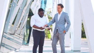Modern ofis binasının önünde kendinden emin Afro-Amerikan iş adamı ve meslektaşı. Finansal yatırımcılar dışarıda konuşuyorlar. Bankacılık ve iş.