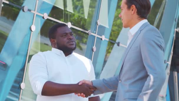 Magabiztos afro-amerikai üzletember és kollégája a modern irodaház előtt. A pénzügyi befektetők a szabadban beszélnek. Bankok és vállalkozások. — Stock videók