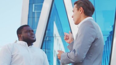 Modern ofis binasının önünde kendinden emin Afro-Amerikan iş adamı ve meslektaşı. Finansal yatırımcılar dışarıda konuşuyorlar. Bankacılık ve iş.