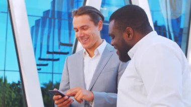 Modern ofis binasının önünde kendinden emin Afro-Amerikan iş adamı ve meslektaşı. Finansal yatırımcılar dışarıda konuşuyorlar. Bankacılık ve iş.