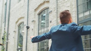 Genç ve başarılı bir iş adamı sokakta dans ediyor. Sıradan giysili bir adam. İş, serbest meslek ve uzak çalışma.