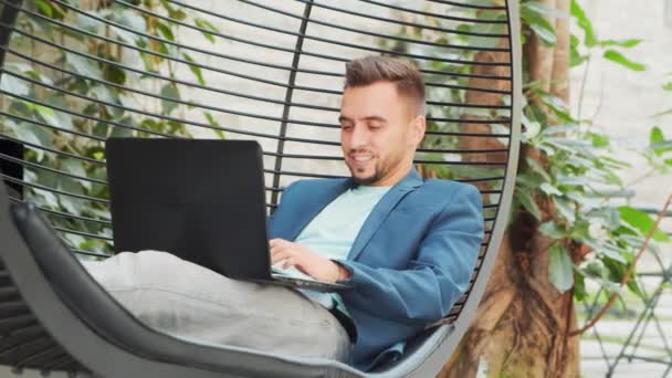 Joven empresario caucásico exitoso trabaja en un salón con una computadora. Negocios, freelance y trabajo remoto. — Vídeos de Stock