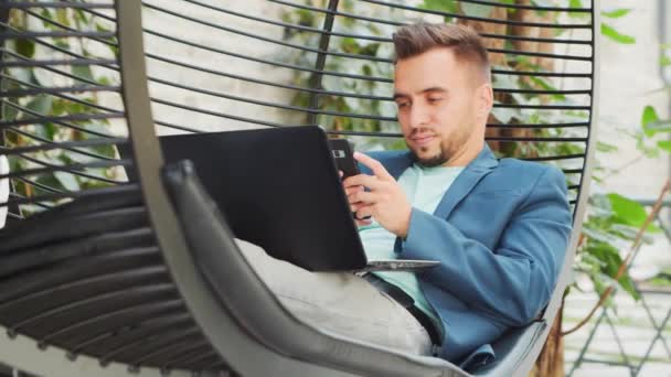 Młody, odnoszący sukcesy biały biznesmen pracuje w salonie przy użyciu komputera. Biznes, praca na własny rachunek i praca zdalna. — Wideo stockowe