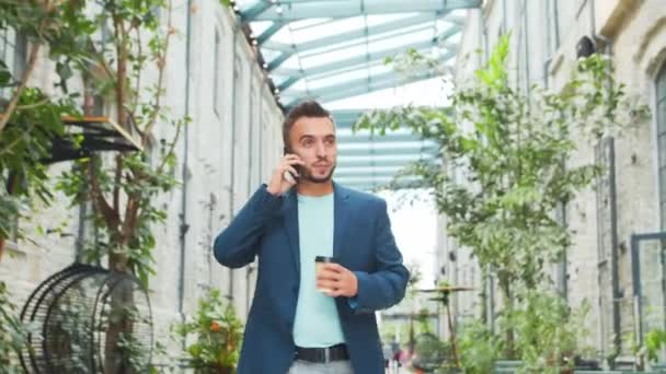 Un joven empresario exitoso está caminando por la calle. Un hombre con ropa casual. Negocios, freelance y trabajo remoto. — Vídeos de Stock