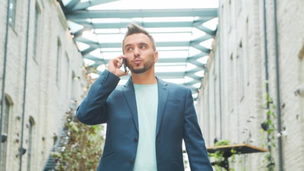 Un joven empresario exitoso está trabajando al aire libre con un teléfono inteligente. Un hombre con ropa casual. Negocios, freelance y trabajo remoto. — Vídeos de Stock