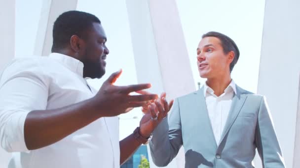 Självsäker afroamerikansk affärsman och hans kollega framför en modern kontorsbyggnad. Finansiella investerare pratar utomhus. Banker och företag. — Stockvideo