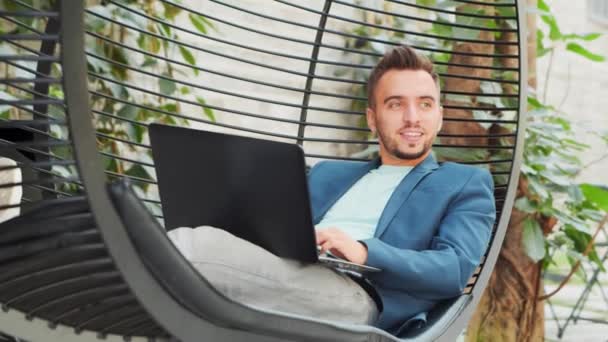 Joven empresario caucásico exitoso trabaja en un salón con una computadora. Negocios, freelance y trabajo remoto. — Vídeos de Stock