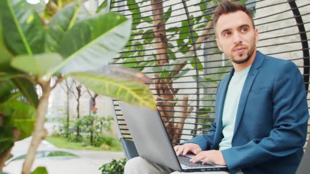 Joven empresario caucásico exitoso trabaja en un salón con una computadora. Negocios, freelance y trabajo remoto. — Vídeos de Stock