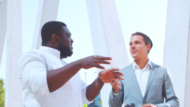 Впевнений афроамериканський бізнесмен і його колега перед сучасним офісним будинком. Фінансові інвестори розмовляють надворі. Банк і бізнес. — стокове відео